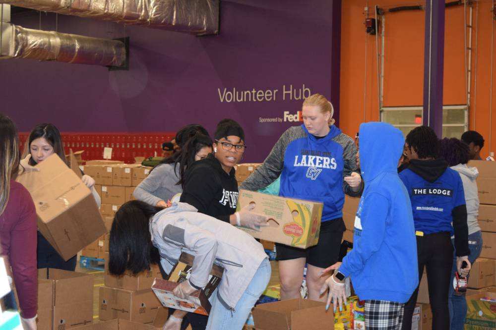 Photo of students working hard packing boxes at food bank